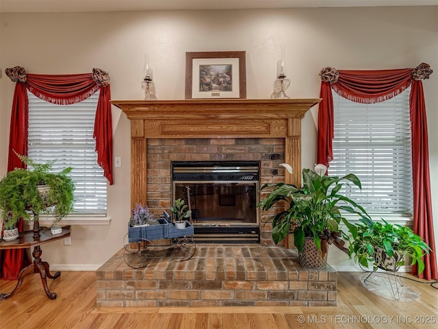 living area featuring a fireplace, plenty of natural light, baseboards, and wood finished floors