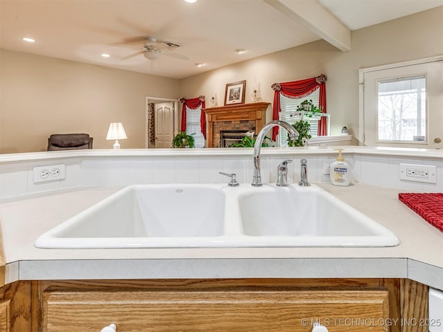 room details featuring recessed lighting, a fireplace, a sink, light countertops, and beamed ceiling