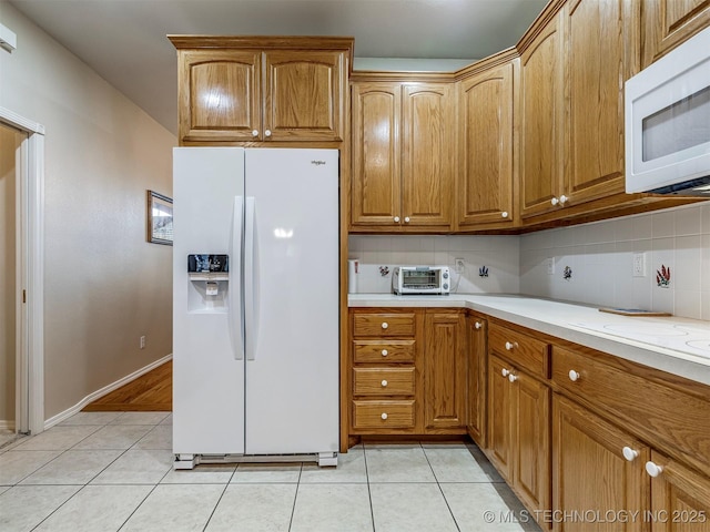 kitchen with white appliances, light tile patterned floors, decorative backsplash, and light countertops