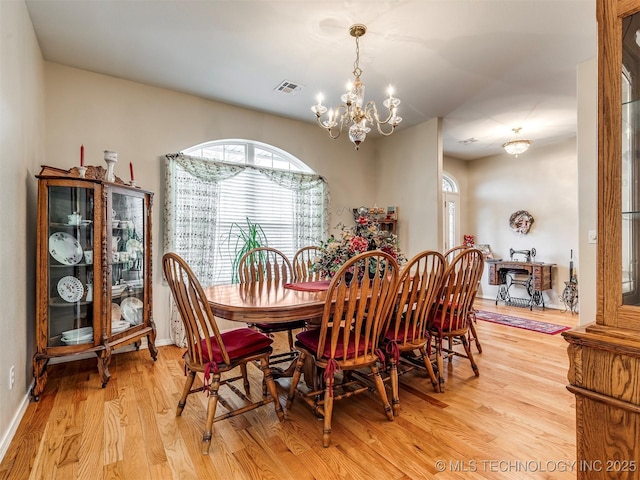 dining room with visible vents, a chandelier, light wood-style flooring, and baseboards