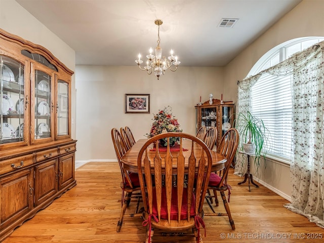 dining space featuring light wood-style floors, baseboards, visible vents, and a chandelier