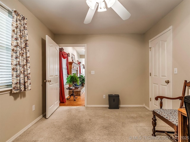 living area with a ceiling fan, light carpet, and baseboards