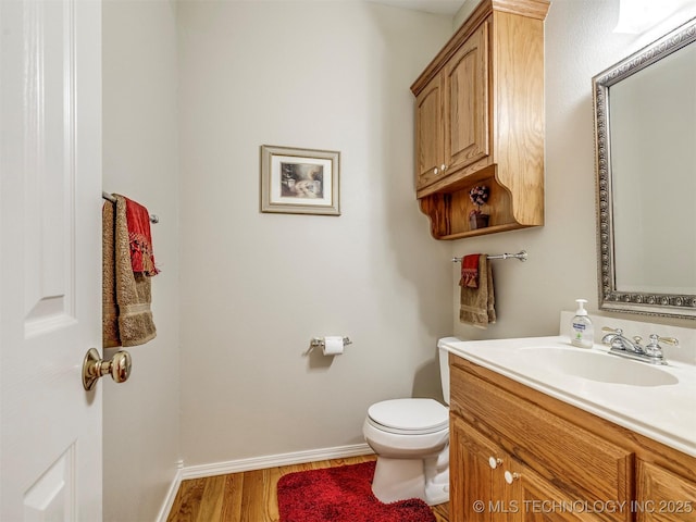 bathroom with toilet, baseboards, wood finished floors, and vanity