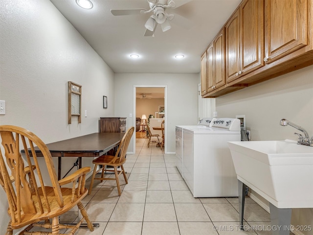 clothes washing area featuring light tile patterned floors, a sink, a ceiling fan, independent washer and dryer, and cabinet space