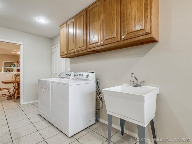 washroom featuring light tile patterned floors, a sink, baseboards, independent washer and dryer, and cabinet space