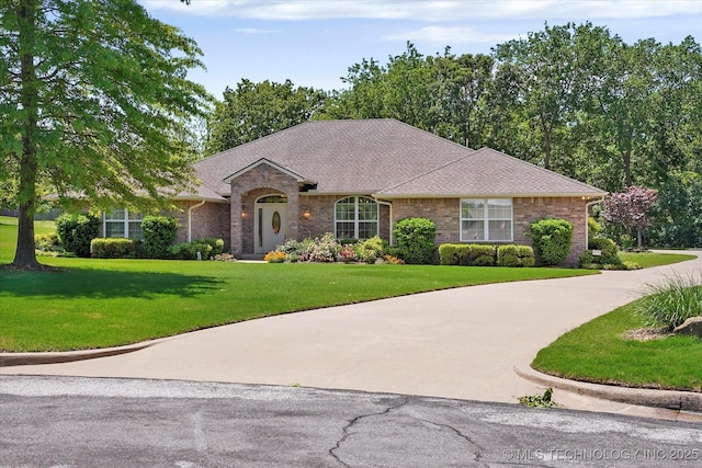 single story home featuring curved driveway, a shingled roof, a front lawn, and brick siding