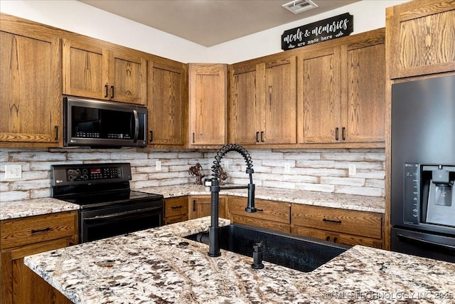 kitchen featuring stainless steel microwave, black electric range oven, decorative backsplash, fridge with ice dispenser, and a sink