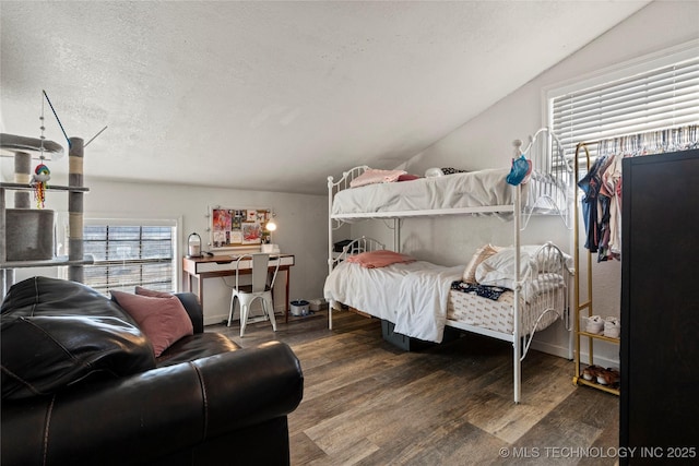 bedroom with lofted ceiling, a textured ceiling, baseboards, and wood finished floors