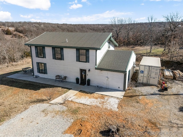 view of front of property with a shingled roof and a patio