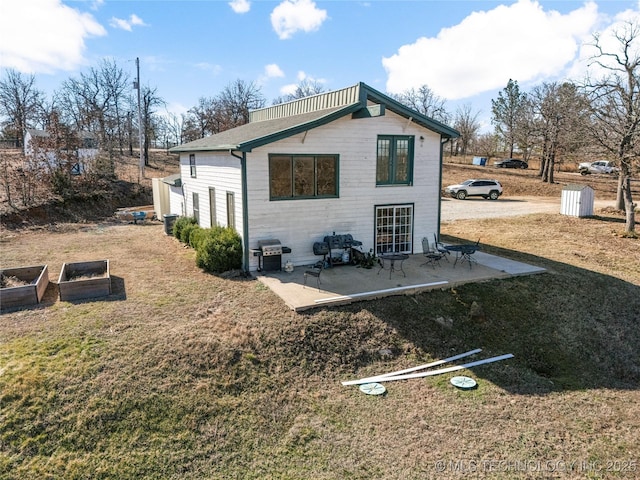 rear view of house featuring a yard, a vegetable garden, and a patio