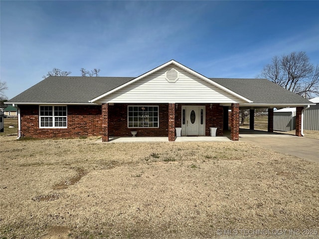 ranch-style house with a carport, driveway, brick siding, and a shingled roof