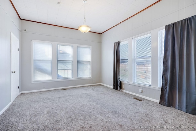 unfurnished room featuring plenty of natural light, visible vents, ornamental molding, and carpet flooring