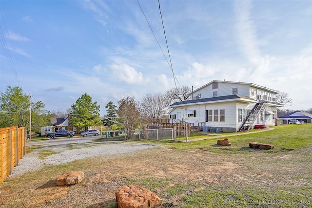 view of yard with fence, central AC unit, and stairs