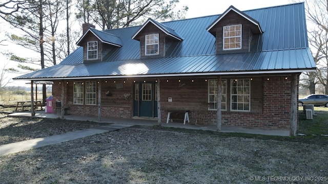 view of front of house with metal roof, a porch, and brick siding