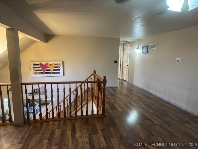 hall with visible vents, an upstairs landing, and wood finished floors