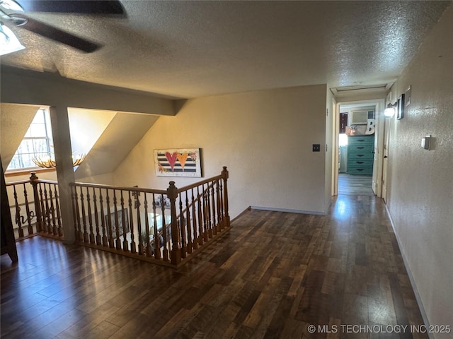 hall with a textured wall, lofted ceiling with beams, a textured ceiling, baseboards, and hardwood / wood-style flooring