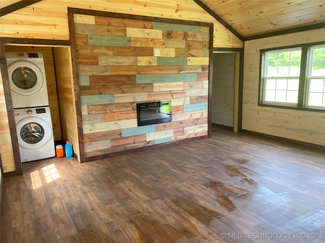 unfurnished living room with lofted ceiling, stacked washer / drying machine, a fireplace, and wooden walls