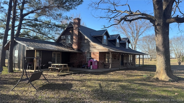 exterior space with french doors, brick siding, a patio, a chimney, and metal roof