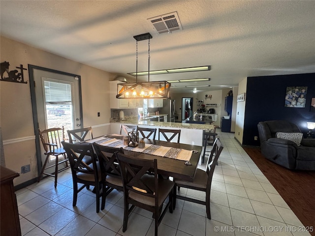 dining space featuring visible vents, a textured ceiling, and light tile patterned flooring