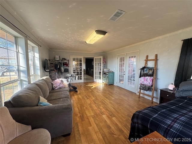 bedroom with french doors, multiple windows, wood finished floors, and visible vents