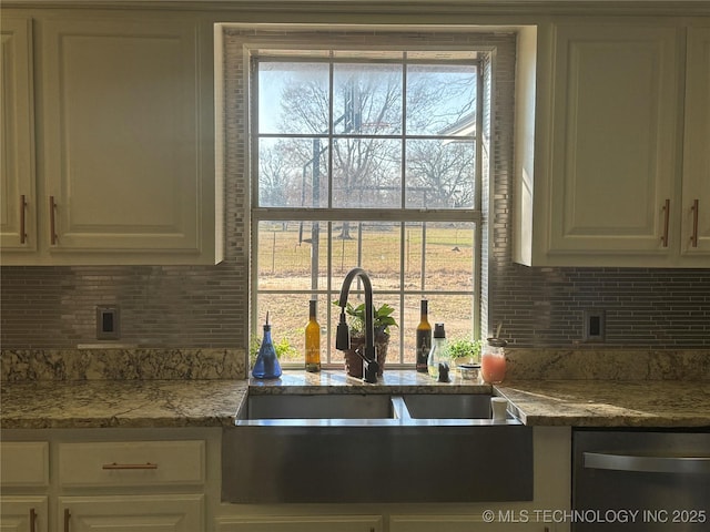 kitchen with dishwasher, a sink, white cabinetry, and decorative backsplash