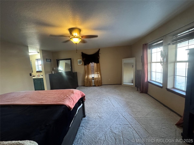 bedroom featuring a ceiling fan, a textured ceiling, and light colored carpet