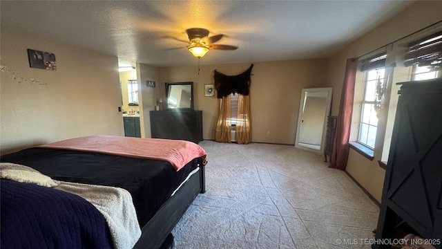 bedroom featuring light carpet, ceiling fan, baseboards, and a textured ceiling