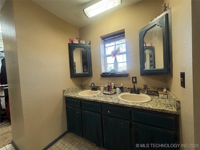 bathroom featuring vaulted ceiling, double vanity, a sink, and a textured wall