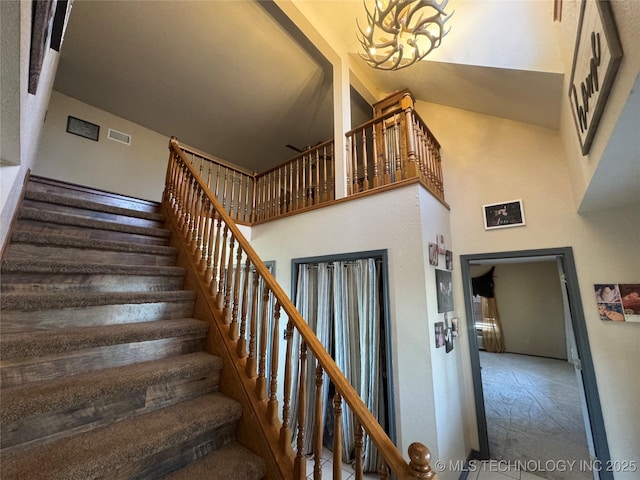 stairs featuring high vaulted ceiling, visible vents, and an inviting chandelier