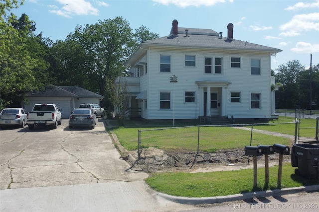 view of front of property featuring a fenced front yard, a front yard, and a detached garage