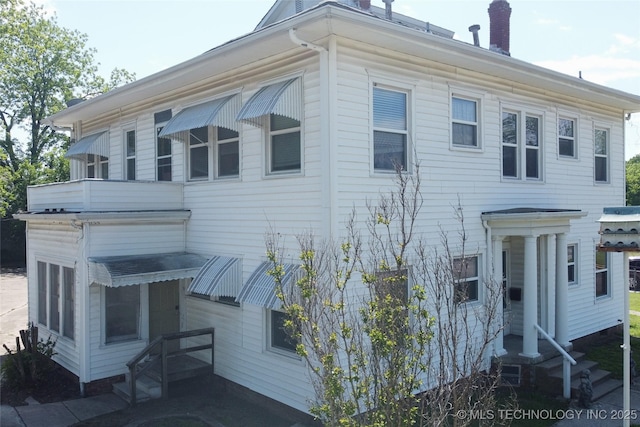 view of home's exterior with entry steps and a chimney