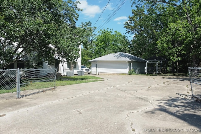 view of front facade featuring central air condition unit, a detached garage, and fence