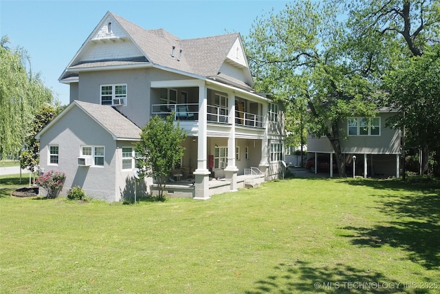 back of property with a balcony, a shingled roof, cooling unit, and a lawn