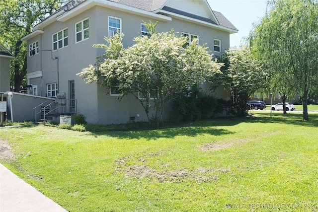 view of property exterior with a shingled roof, a lawn, and stucco siding