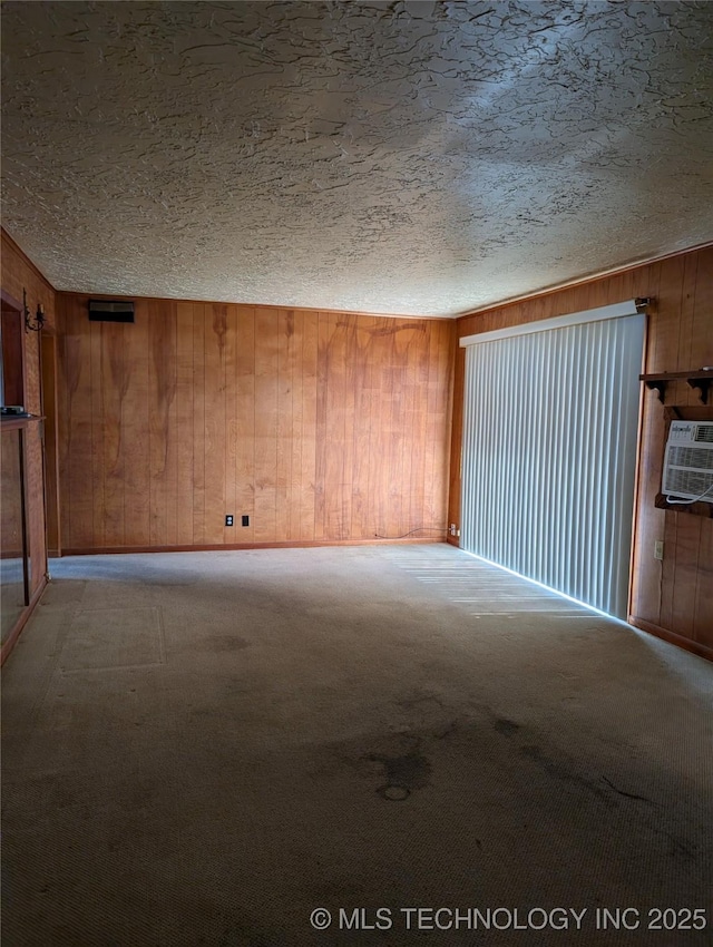 carpeted empty room featuring a textured ceiling, wood walls, a wall unit AC, and baseboards