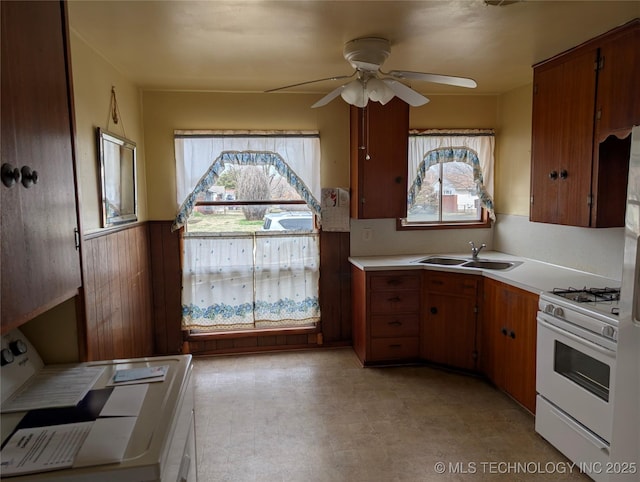 kitchen featuring a wealth of natural light, white range with gas stovetop, light countertops, and a sink