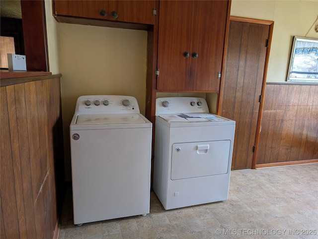 washroom featuring a wainscoted wall, wood walls, cabinet space, and washer and dryer