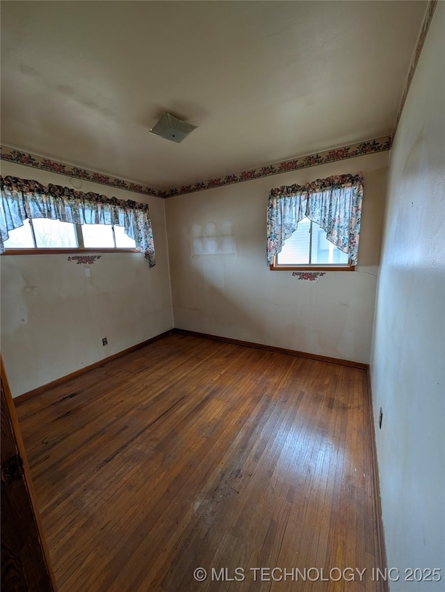 unfurnished room with hardwood / wood-style flooring and baseboards