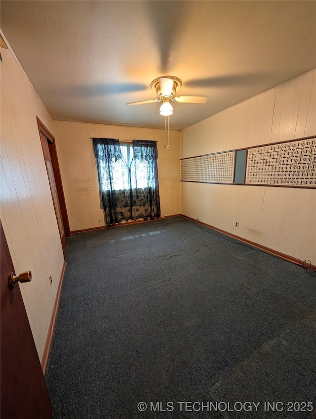 spare room with a ceiling fan, dark carpet, and mail area