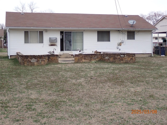 back of house featuring entry steps, roof with shingles, and a lawn