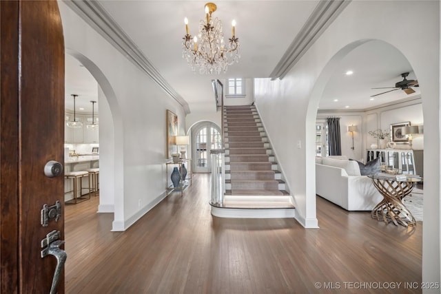 foyer entrance featuring arched walkways, crown molding, and wood finished floors