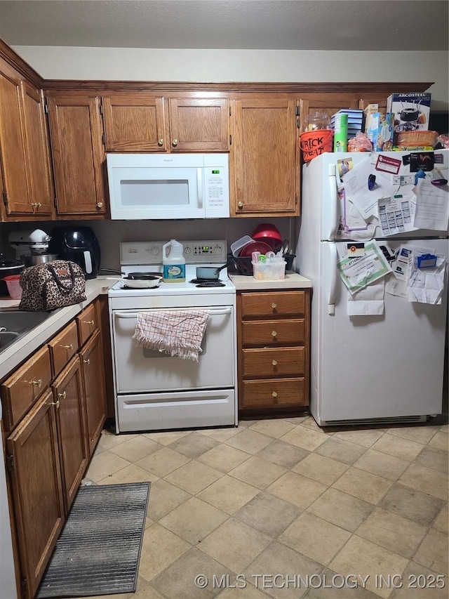 kitchen featuring white appliances, brown cabinetry, and light countertops