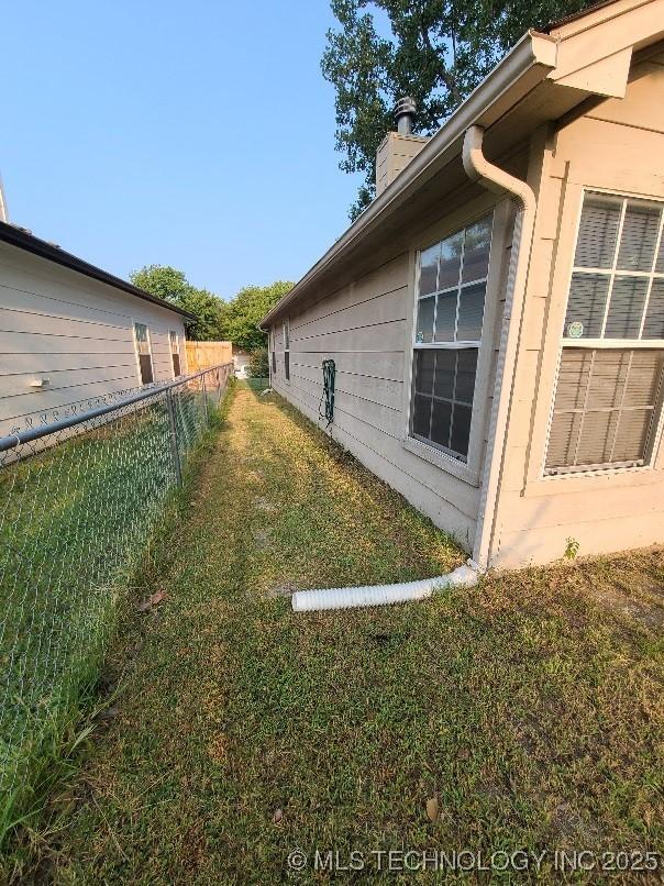 view of home's exterior with a chimney, fence, and a yard