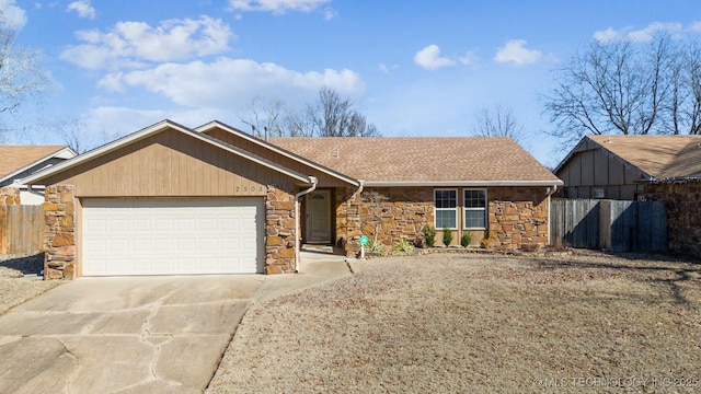 ranch-style house featuring roof with shingles, concrete driveway, fence, a garage, and stone siding