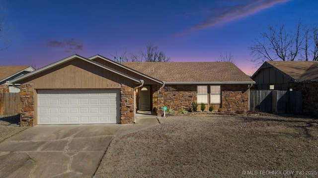 ranch-style house featuring driveway, a shingled roof, stone siding, an attached garage, and fence