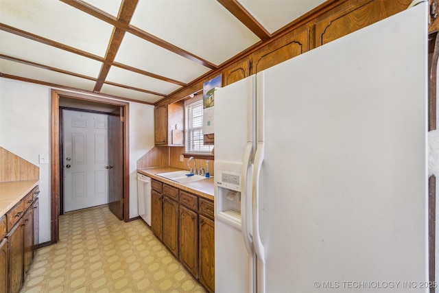 kitchen with brown cabinetry, white appliances, light countertops, and light floors