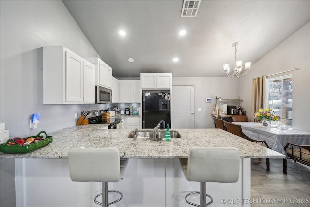 kitchen with a peninsula, white cabinetry, visible vents, and stainless steel appliances