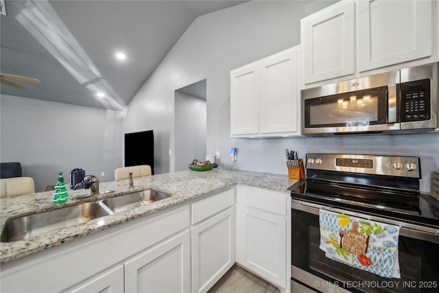 kitchen featuring lofted ceiling, white cabinetry, stainless steel appliances, and a sink