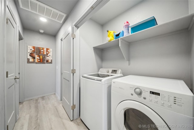 clothes washing area with laundry area, visible vents, baseboards, light wood-style flooring, and separate washer and dryer