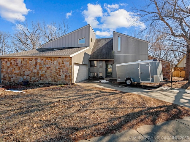 rear view of house featuring driveway, roof with shingles, and an attached garage